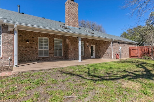back of property with fence, a chimney, a yard, a patio area, and a gate