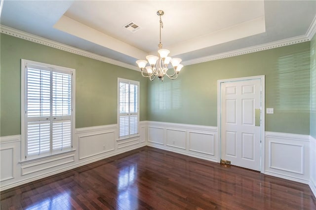 empty room with visible vents, dark wood finished floors, wainscoting, a raised ceiling, and a notable chandelier