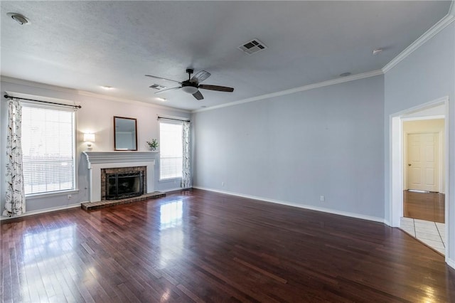 unfurnished living room featuring visible vents, a fireplace with raised hearth, wood finished floors, crown molding, and ceiling fan