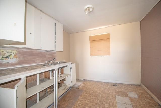 kitchen with white cabinetry, light countertops, and baseboards