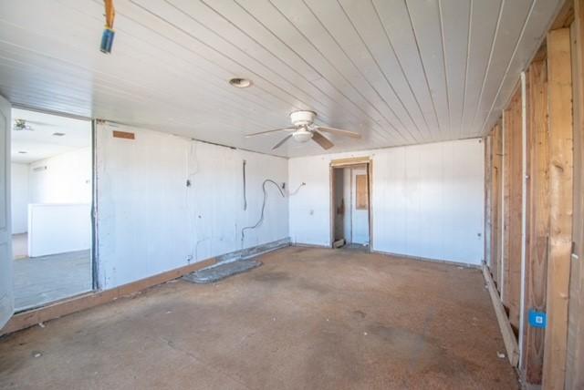 unfurnished room with wood ceiling, concrete flooring, and ceiling fan