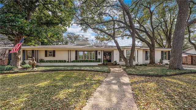 ranch-style house featuring brick siding, a chimney, a front lawn, and fence