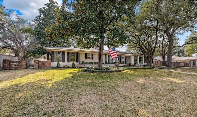 ranch-style home featuring brick siding, a front lawn, and fence