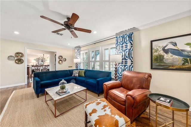 living room featuring visible vents, a ceiling fan, wood finished floors, crown molding, and baseboards