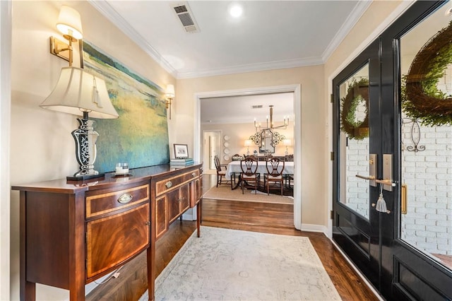 foyer entrance with dark wood-style floors, visible vents, and crown molding
