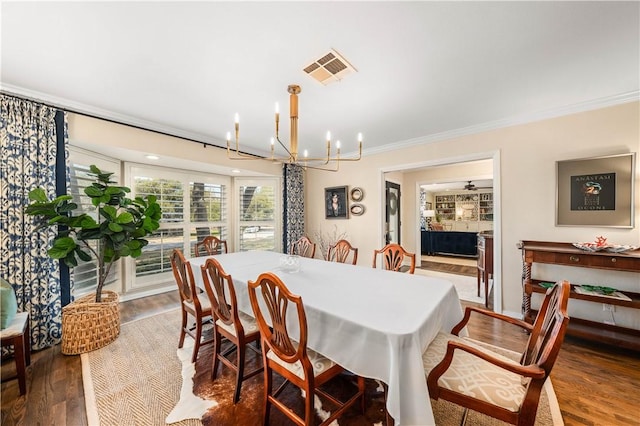 dining room with visible vents, ornamental molding, an inviting chandelier, and wood finished floors