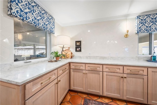 kitchen featuring light tile patterned floors, light brown cabinets, light stone countertops, and crown molding
