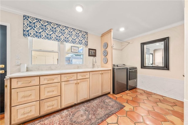 kitchen with light brown cabinetry, a sink, crown molding, and separate washer and dryer