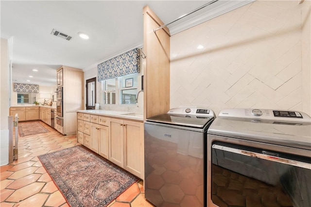 washroom featuring visible vents, ornamental molding, laundry area, washer and dryer, and a sink