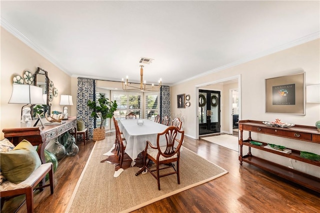 dining room with visible vents, ornamental molding, wood finished floors, an inviting chandelier, and baseboards