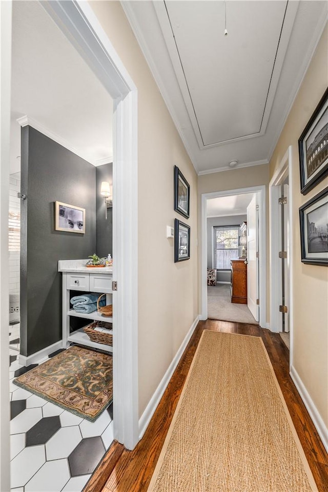 corridor with baseboards, dark wood-type flooring, attic access, and crown molding