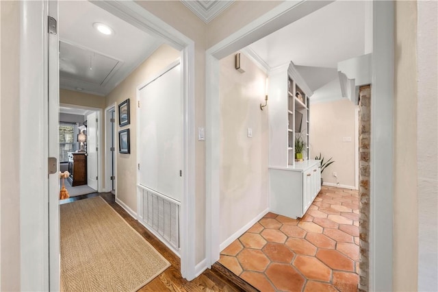 corridor featuring attic access, baseboards, visible vents, and ornamental molding