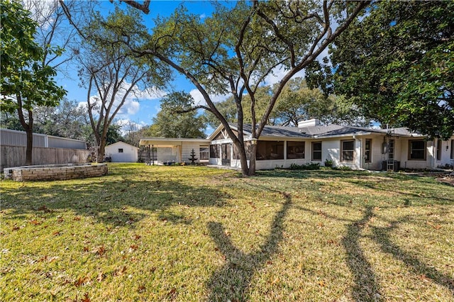 back of property featuring central AC unit, fence, a sunroom, a chimney, and a lawn