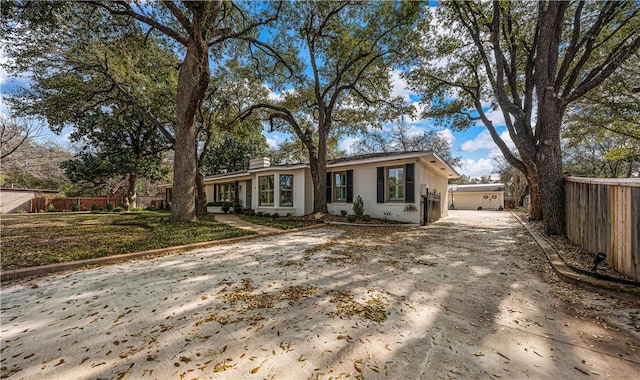 ranch-style house with a chimney, concrete driveway, and fence