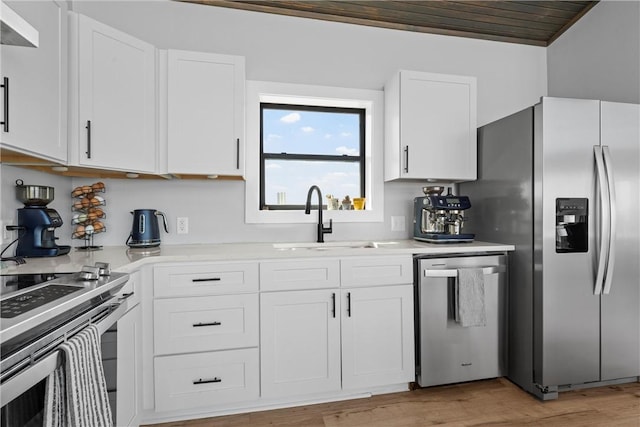 kitchen featuring light wood-style flooring, appliances with stainless steel finishes, light countertops, white cabinets, and a sink