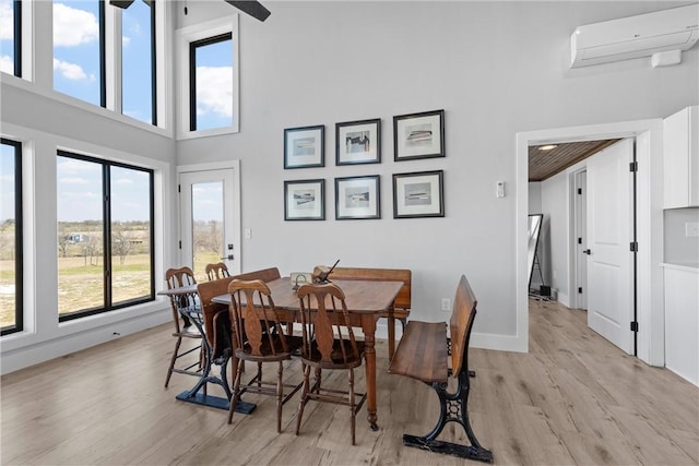 dining space featuring a wall unit AC, a wealth of natural light, and light wood-style floors
