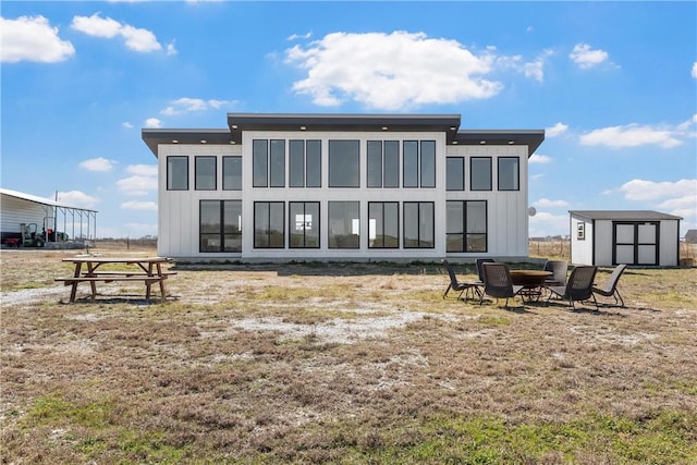 rear view of house with an outdoor structure, a storage unit, a fire pit, and board and batten siding
