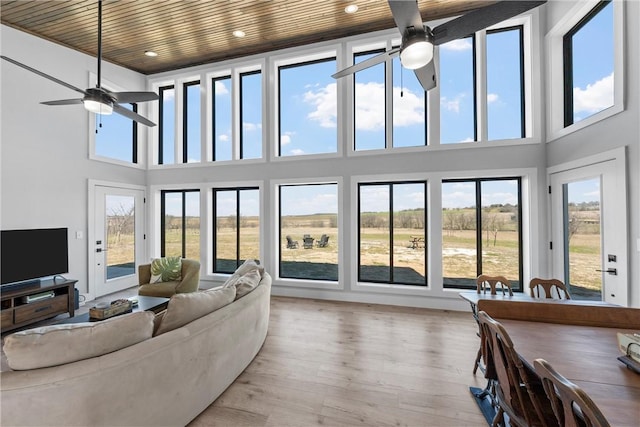 living area featuring recessed lighting, a high ceiling, ceiling fan, and wood finished floors