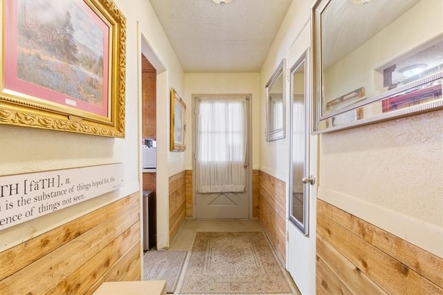 doorway featuring wainscoting, wooden walls, and a textured ceiling