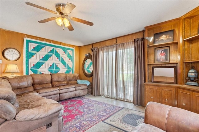 carpeted living area with wooden walls, a textured ceiling, and ceiling fan