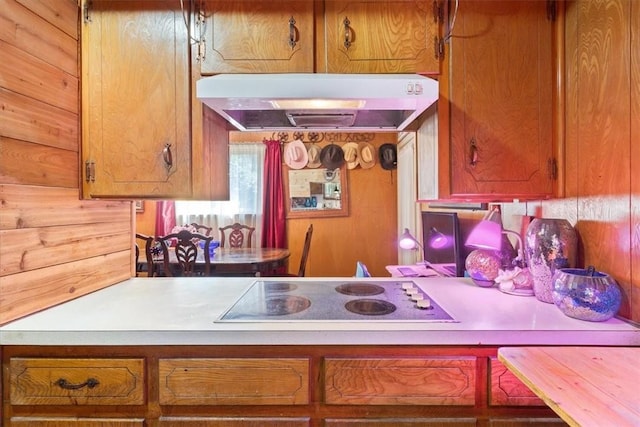 411 Brookwood Dr, Woodway, TX 76712 - kitchen with range hood, white electric stovetop, light countertops, wood walls, and brown cabinets