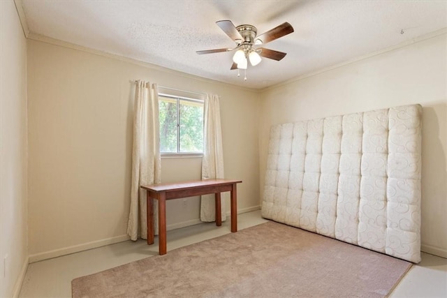 carpeted spare room with baseboards, a ceiling fan, and crown molding