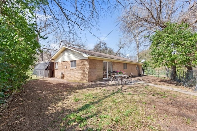 rear view of property with brick siding, a patio, and fence