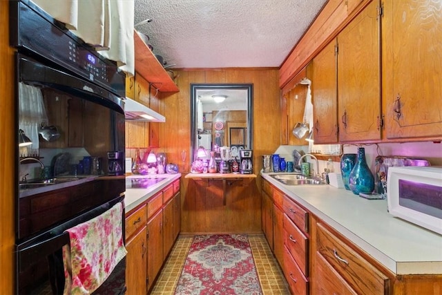 kitchen with black electric cooktop, light countertops, a sink, white microwave, and a textured ceiling
