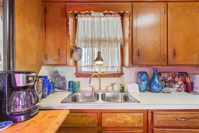 kitchen with light countertops, a sink, and brown cabinets