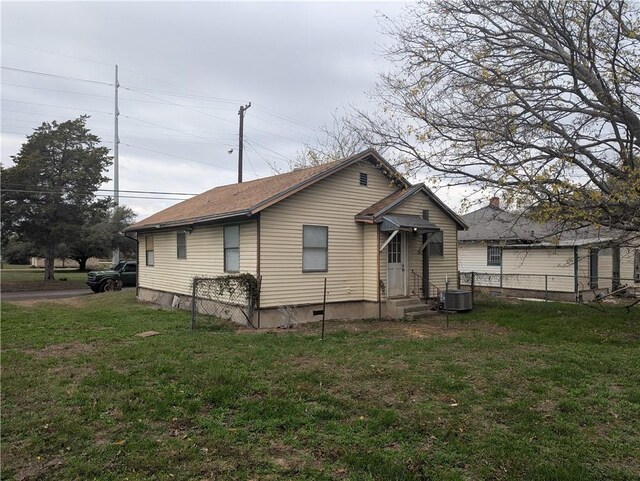 back of property featuring cooling unit, a lawn, fence, and a shingled roof