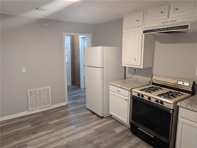 kitchen with under cabinet range hood, visible vents, white appliances, and wood finished floors