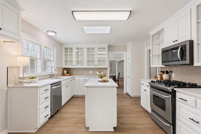 kitchen featuring open shelves, a sink, a center island, stainless steel appliances, and white cabinets