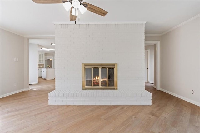 unfurnished living room featuring a brick fireplace, crown molding, baseboards, wood finished floors, and a ceiling fan