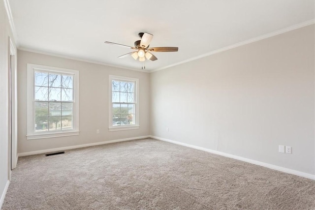 carpeted spare room with ceiling fan, baseboards, visible vents, and ornamental molding