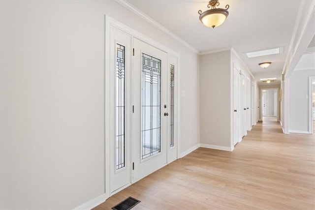 entrance foyer with crown molding, light wood-style flooring, baseboards, and visible vents