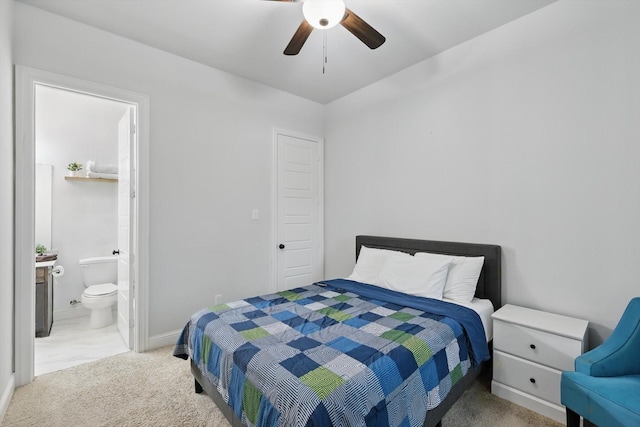 bedroom with light colored carpet, ceiling fan, baseboards, and ensuite bath