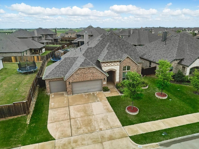 french country inspired facade featuring a residential view, concrete driveway, a trampoline, an attached garage, and a shingled roof