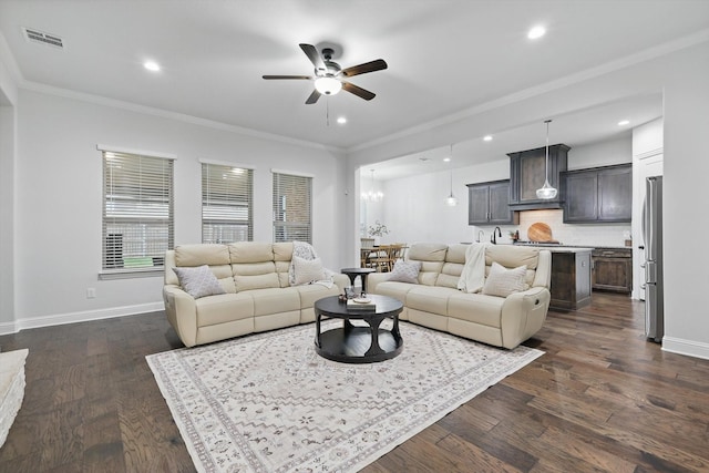 living room featuring ceiling fan with notable chandelier, baseboards, visible vents, and crown molding