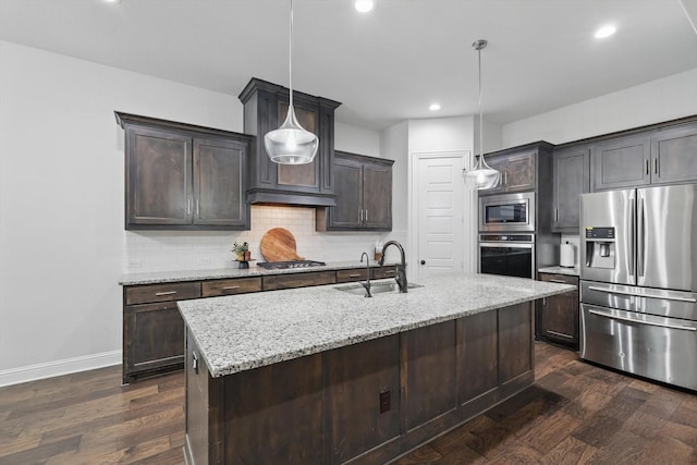 kitchen with a sink, tasteful backsplash, dark brown cabinetry, light stone countertops, and appliances with stainless steel finishes