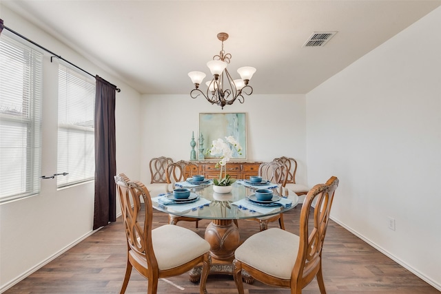 dining space with a chandelier, visible vents, baseboards, and wood finished floors