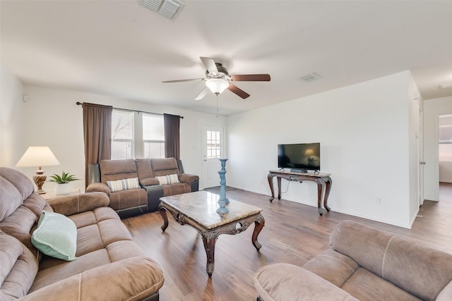 living area featuring visible vents, baseboards, a ceiling fan, and wood finished floors