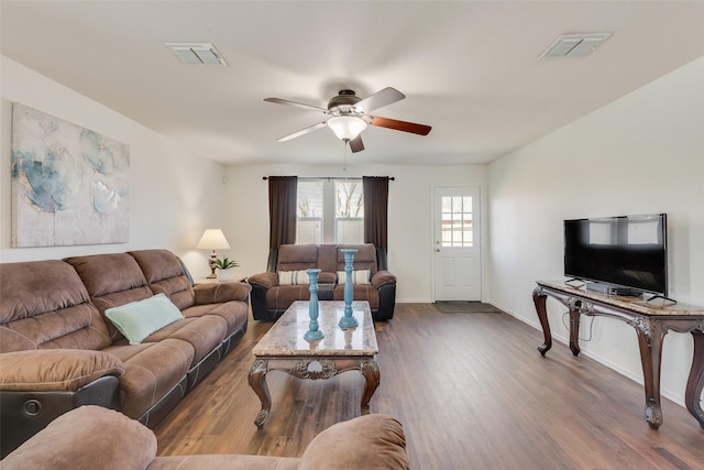 living area featuring visible vents, wood finished floors, baseboards, and ceiling fan