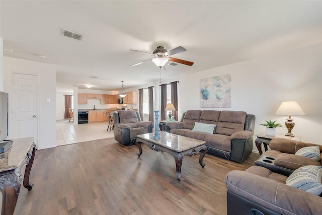 living room with visible vents, wine cooler, wood finished floors, and a ceiling fan