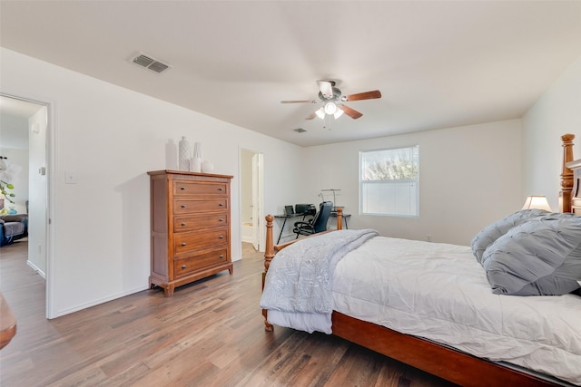 bedroom featuring light wood-type flooring, visible vents, ensuite bath, baseboards, and ceiling fan