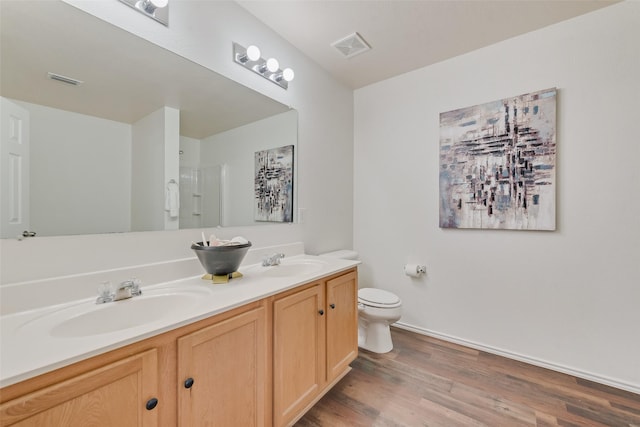 bathroom featuring double vanity, toilet, wood finished floors, and a sink