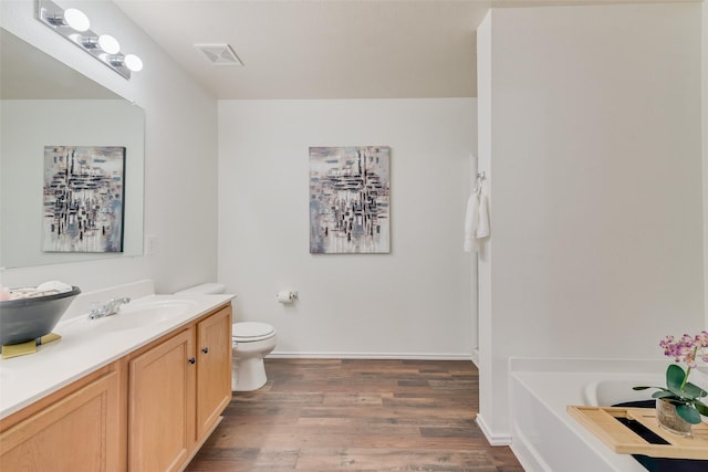 full bath with visible vents, toilet, a garden tub, wood finished floors, and vanity