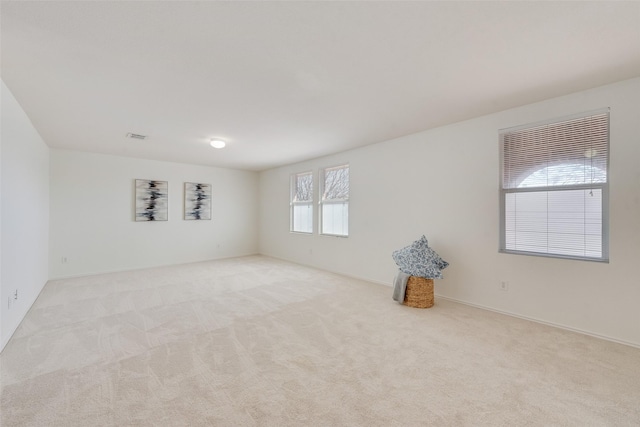 spare room with visible vents and light colored carpet