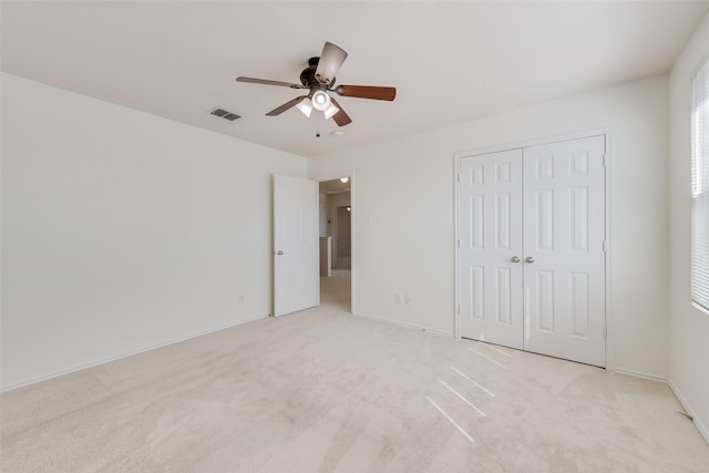 unfurnished bedroom featuring visible vents, light colored carpet, a closet, and a ceiling fan