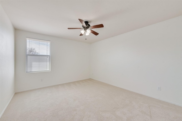empty room with light colored carpet, baseboards, and a ceiling fan