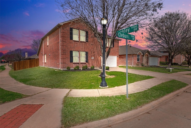 view of front of property with a front lawn, fence, concrete driveway, a garage, and brick siding